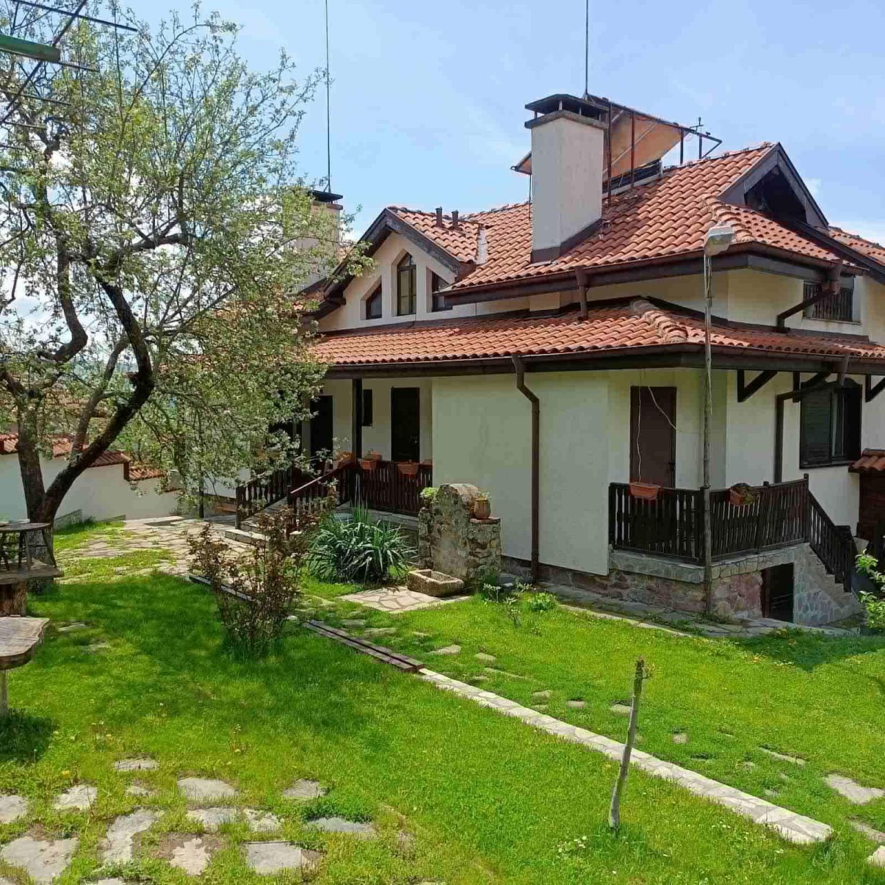 Къщата, огряна от слънце, и зеленият двор